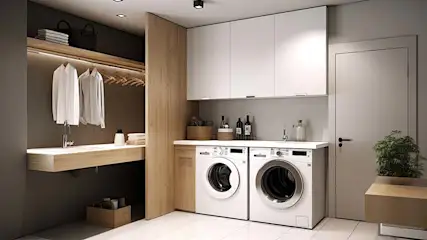 Witte kasten boven wasmachines in een wasruimte met houten accenten. Een deur en plant zijn rechts zichtbaar.
