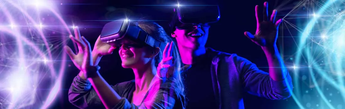 Twee mensen dragen VR-headsets, lachen en reiken uit met hun handen, ondergedompeld in een kleurrijke, virtuele wereld.