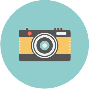 Een camera met een gele voorkant en een zwarte lens staat tegen een blauwe cirkelvormige achtergrond.