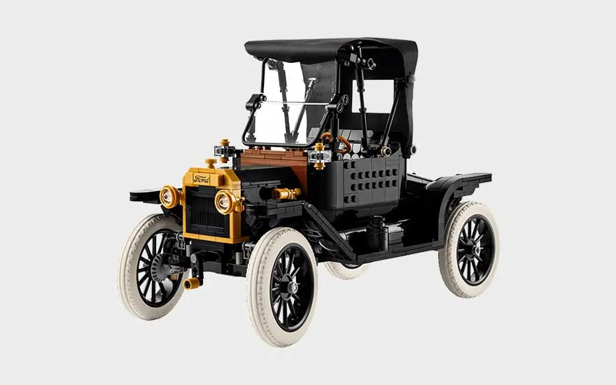 Klassieke zwarte LEGO Ford-auto met witte banden, gouden koplampen, open cabine, stoffen dak en vintage uitstraling.
