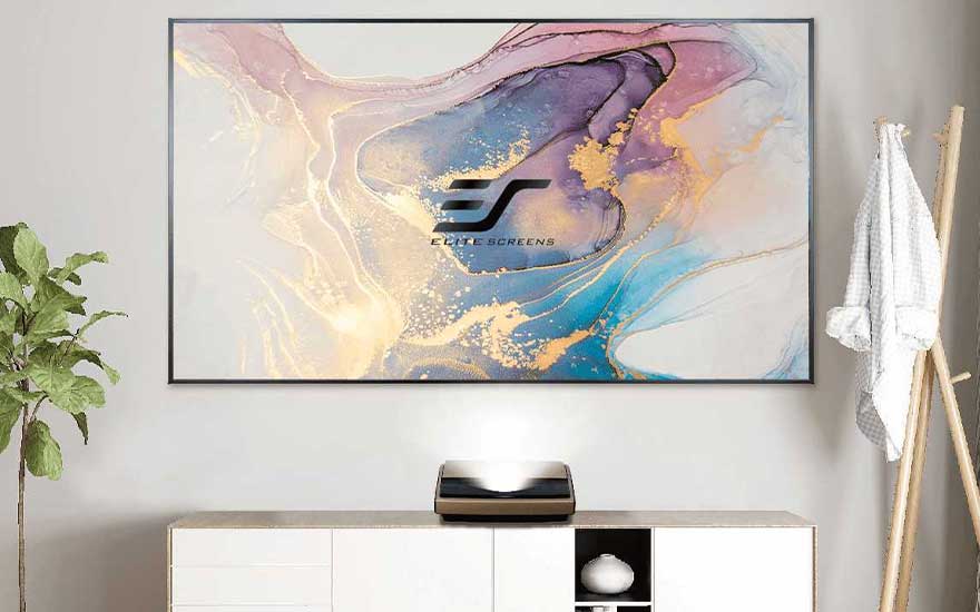 An ultra-short-throw projector displays a colourful image on a large screen above a modern white cabinet at home.