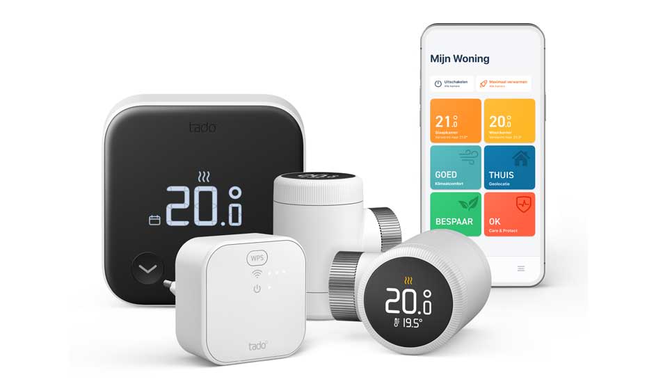Een tado-set met zwarte thermostaat, witte wifi-bridge en twee slimme radiatorknoppen, plus een smartphone met de ‘Mijn Woning’-app.