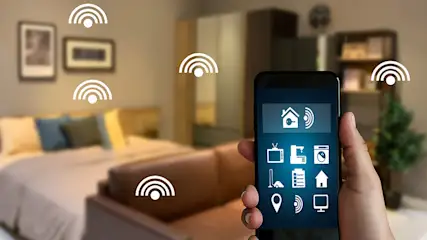 Hand houdt smartphone met smart home app in slaapkamer met bed, kast, plant en wifi symbolen.