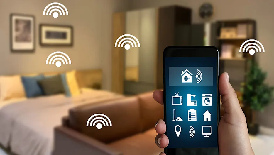 Hand houdt smartphone met smart home app in slaapkamer met bed, kast, plant en wifi symbolen.