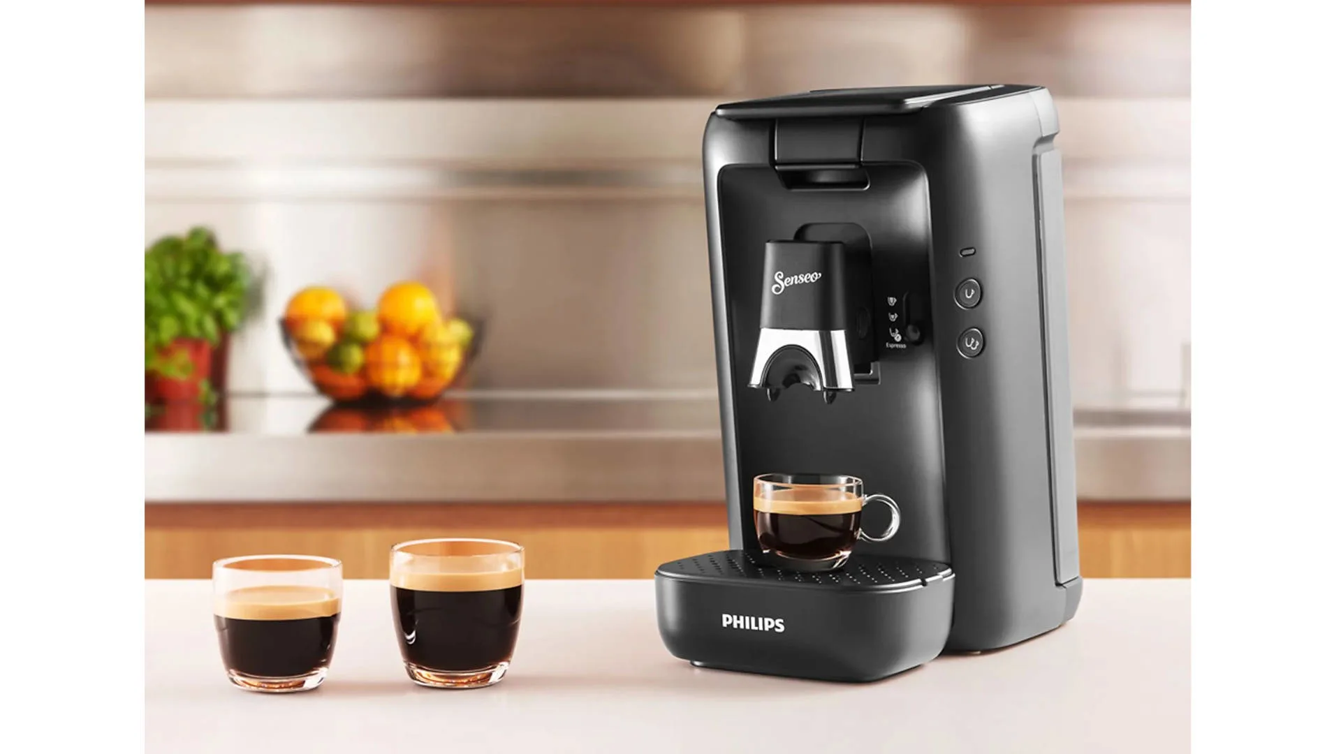 Een zwarte Senseo koffiemachine met Philips logo, met drie kopjes koffie op een aanrecht.