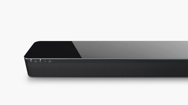 Een zwarte soundbar staat op een witte achtergrond, gezien vanuit een laag perspectief. Het apparaat heeft afgeronde hoeken.