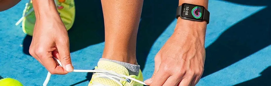 Een sporter strikt felgele veters op een blauwe baan, terwijl een slimme fitnesswatch de kleurrijke activiteitsringen toont.