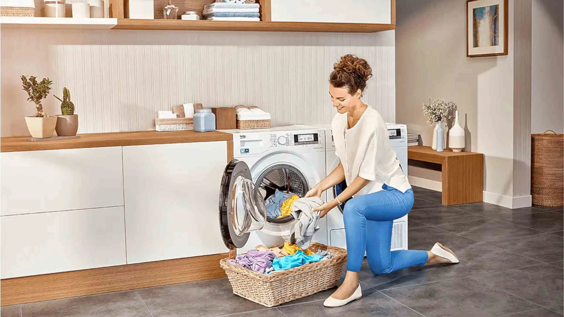Vrouw knielt voor een open wasmachine en haalt wasgoed uit een rieten mand in een wasruimte.