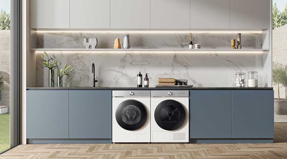 Moderne keuken met blauwe kasten, marmeren achterwand en centraal ingebouwde witte wasmachine en droger naast elkaar.