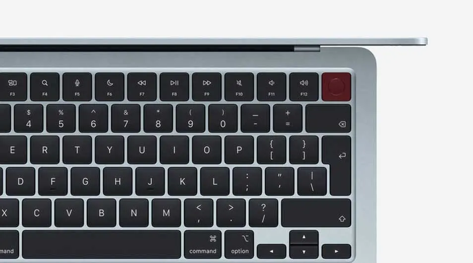 Detailed view of a keyboard with dark keys and a distinctive red Touch ID button in the top right, beneath a slim lid.