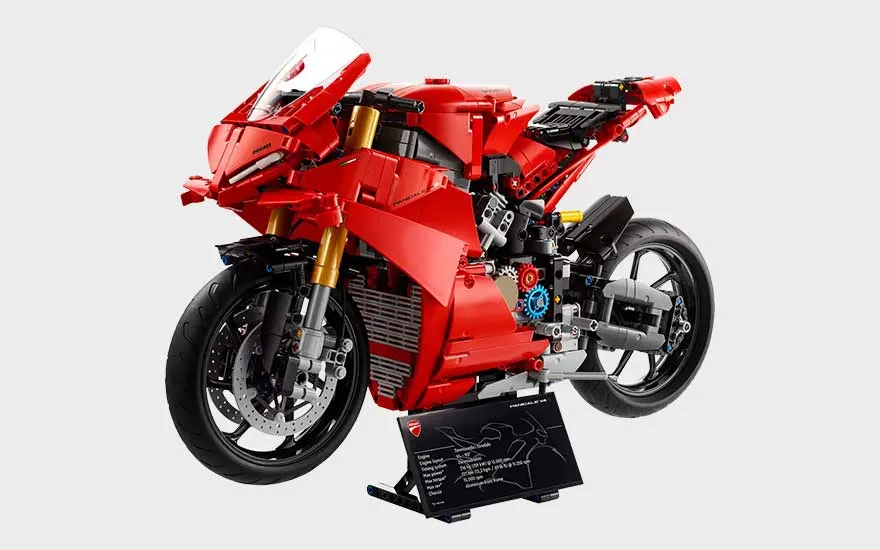 Rode LEGO Ducati-motorfiets op standaard, met sportieve kuip, zwarte wielen, gouden vorken en informatieplaat ervoor.