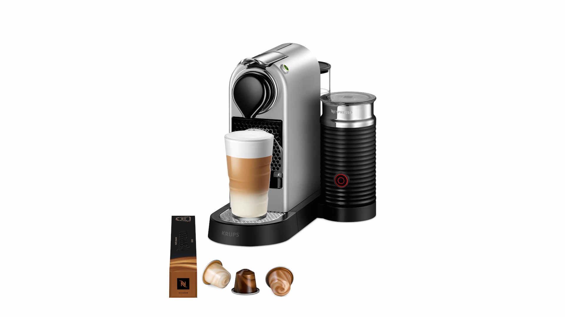 Zilveren Nespresso-apparaat met melkopschuimer, een glas koffie en capsules op een witte achtergrond.