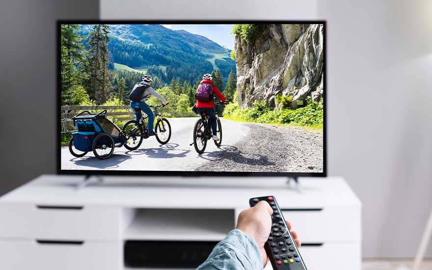 Een vrouw kijkt naar een smart-tv in een moderne woonkamer, waar het beeld gesprekken toont over bezienswaardigheden in Parijs.