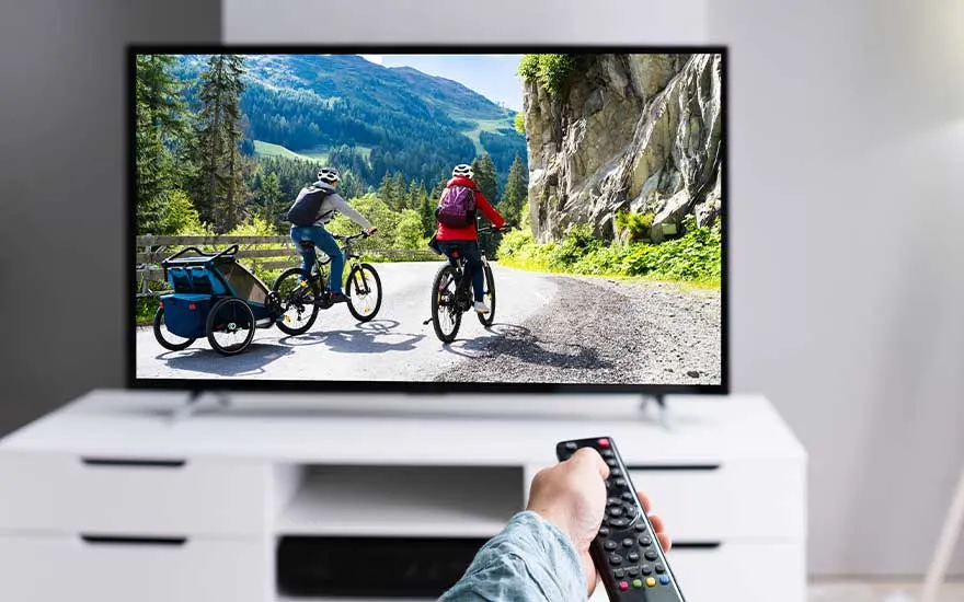 Een vrouw kijkt naar een smart-tv in een moderne woonkamer, waar het beeld gesprekken toont over bezienswaardigheden in Parijs.