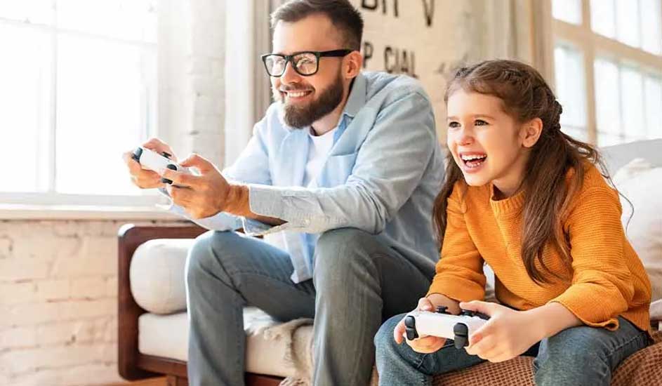Dit is een videogame: Twee mensen zitten samen op een bank, geconcentreerd aan het gamen met controllers in een lichte, gezellige woonkamer.