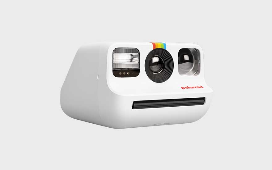 Een witte Polaroid-camera met regenboogstreepjes op een lichte achtergrond; lens, zoeker en flitser duidelijk zichtbaar vooraan.