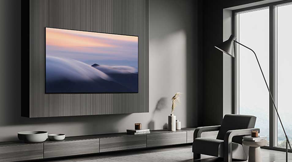 Minimalistisch interieur met een grote tv aan de wand. Grijze meubels, lange ramen en een vloerlamp geven het geheel een luxe uitstraling.