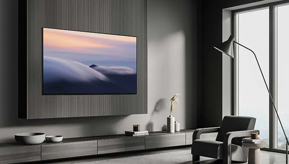 Minimalistisch interieur met een grote tv aan de wand. Grijze meubels, lange ramen en een vloerlamp geven het geheel een luxe uitstraling.