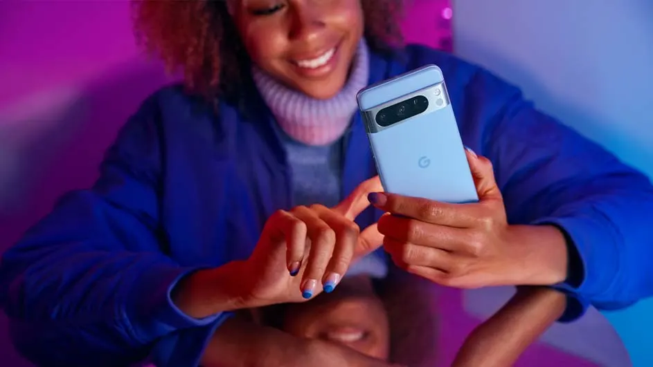 Een persoon houdt een blauwe telefoon vast met een camera aan de achterkant, tegen een paarse en blauwe achtergrond.