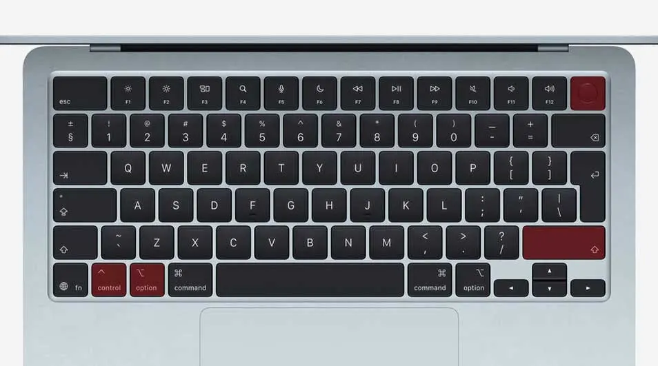 Bovenaanzicht van een volledig toetsenbord met zwarte toetsen, rode functietoetsen en pijltjestoetsen, onderdeel van een slanke zilveren laptop.