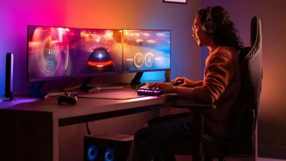 Vrouw met koptelefoon speelt racegame op twee monitoren met een verlicht toetsenbord op een bureau.