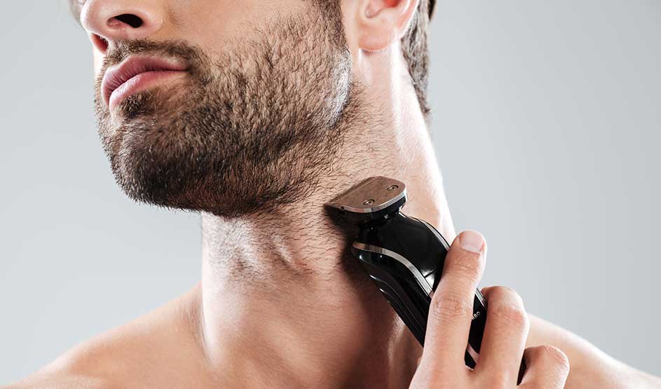 A man shaves his neck and beard line with an electric device; only his chin, neck, and hand are visible in close-up.