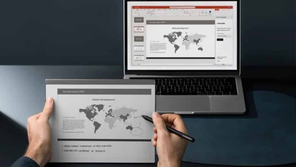 A laptop displays a presentation with a world map, next to a tablet held by hands, and a pen is touching the screen.