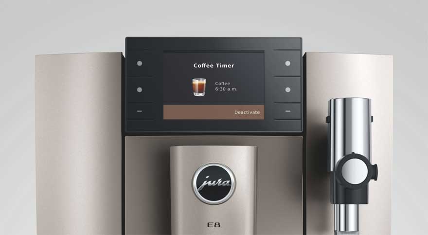 Close-up van een Jura E8 koffiemachine: centraal het display met ‘Coffee Timer’, onder het logo, rechts een melkopschuimer.