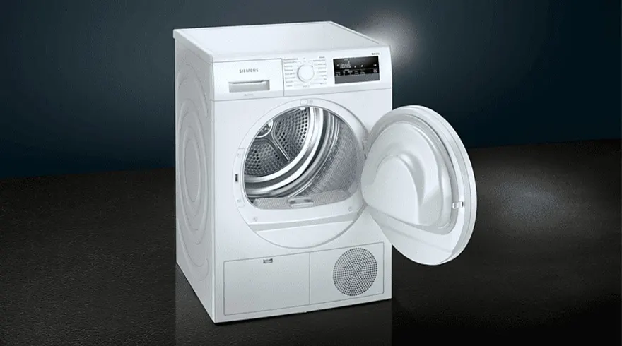 Een witte wasdroger met een open deur staat op een donkere vloer voor een donkere achtergrond.