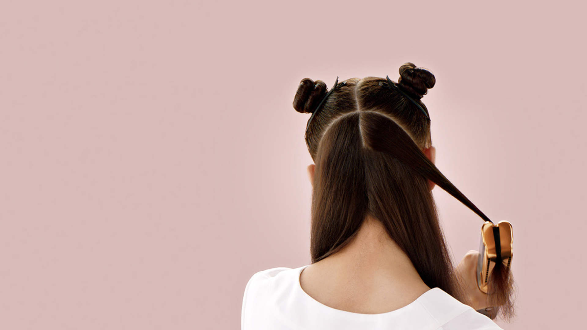 Een persoon met lang haar verdeeld in secties, sommige opgestoken, gebruikt een gouden klem op een pluk haar.