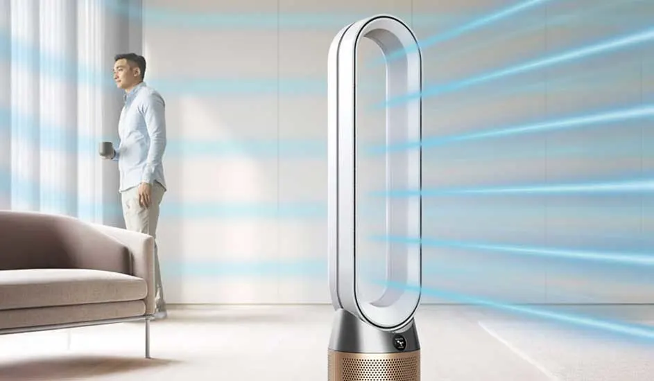 In een moderne woonkamer staat een Dyson luchtreiniger-ventilator die krachtige, frisse lucht uitblaast richting het interieur. Merknaam: Dyson.
