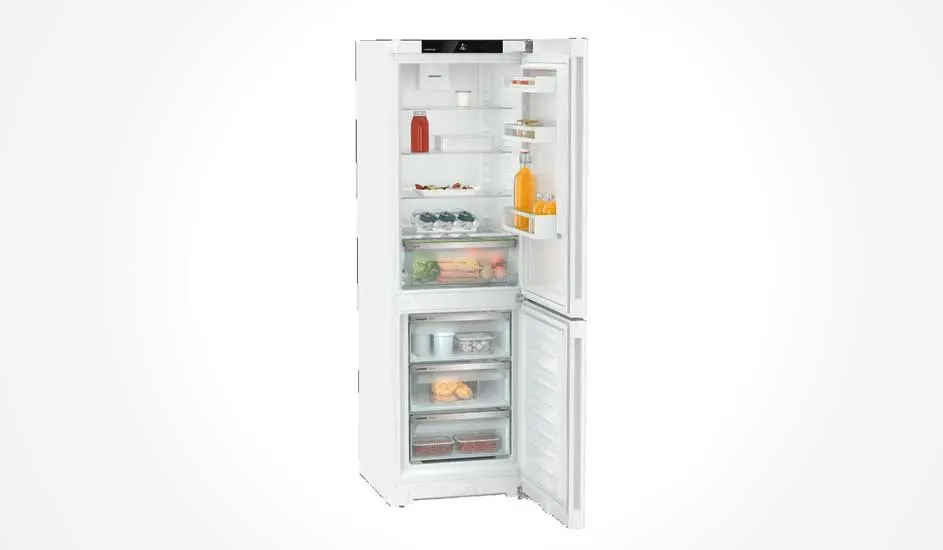 Een witte koelkast met ondervriesvak staat open en is netjes gevuld met flessen, yoghurt, groenten, fruit, diepvriesproducten en pakjes.