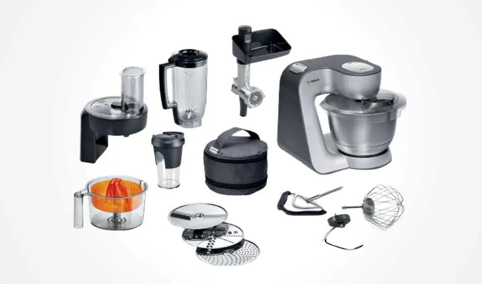 Een keukenmachine-set: mixer met kom en veel accessoires zoals blenderkan, citruspers, raspschijven, beker en vleesmolen op witte achtergrond.