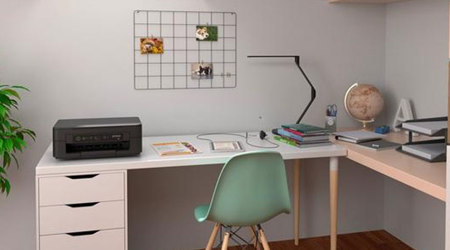 Een bureau met een printer, boeken, een lamp, een wereldbol en een groen plantje in een witte kamer.