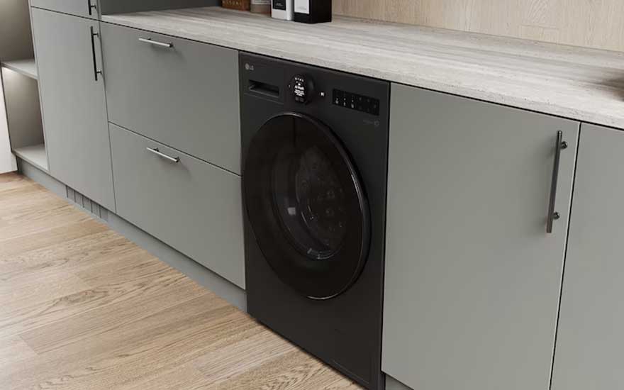 Zwarte LG wasmachine geïntegreerd onder een werkblad tussen grijsgroene kasten, in een strakke moderne bijkeuken.