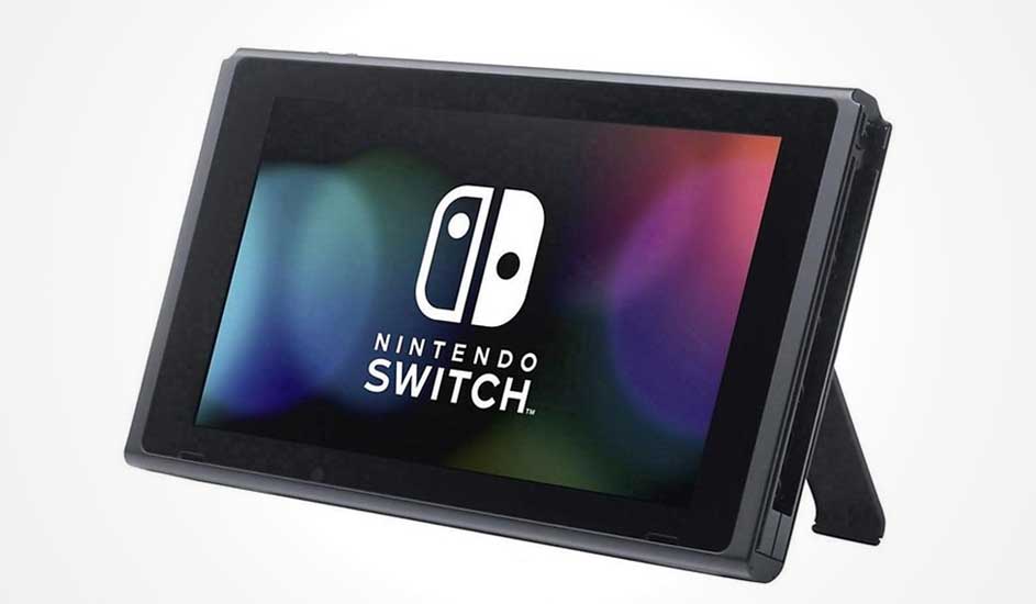 Een zwarte Nintendo Switch staat rechtop op zijn standaard, met het logo groot zichtbaar op een kleurrijk scherm.