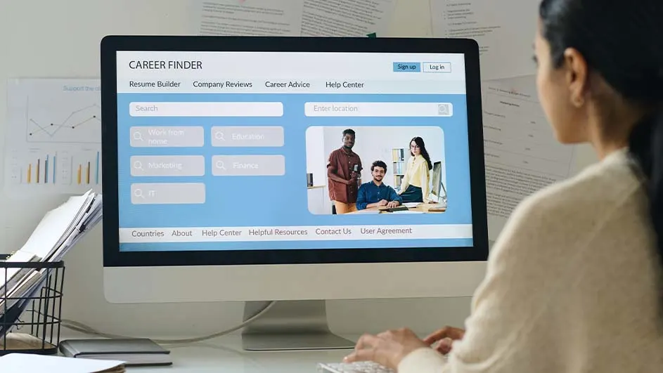 Vrouw typt op een toetsenbord voor een computer met een carrièresite. Papieren en grafieken zijn op de achtergrond.
