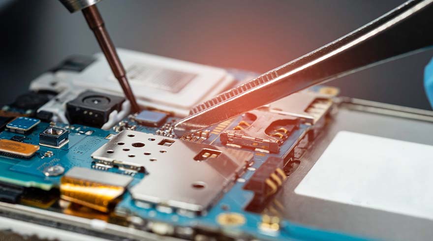 Een blauwe printplaat met zilverkleurige metalen componenten wordt bewerkt met een schroevendraaier en pincet.