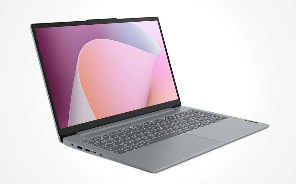 A grey laptop at an angle on white, with a large display showing pink abstract shapes; slim bezels, chiclet keys and a wide touchpad.