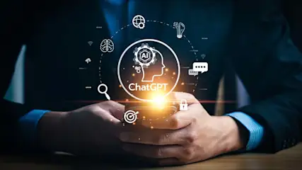 Een persoon houdt een telefoon vast met een ChatGPT logo en AI gerelateerde pictogrammen eromheen.