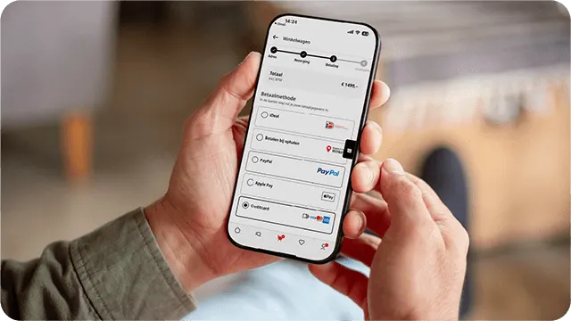 Hand houdt smartphone met afrekenpagina en betaalopties zoals iDEAL, PayPal en Apple Pay.