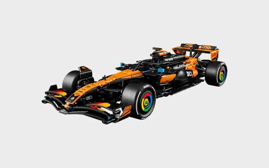 Oranje en zwarte LEGO Formule 1-racewagen met brede banden, lage neus, achtervleugel en kleurrijke details op de wielen.