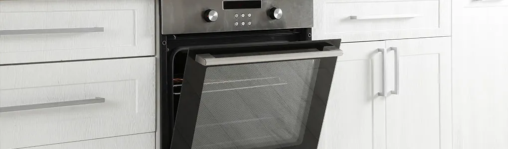 A kitchen view shows an open, dark oven and white cabinets with silver handles.