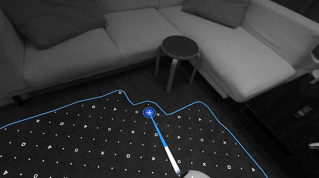 A living room shows a white sofa, small table, and a black surface with white shapes outlined in blue, including a plus sign.