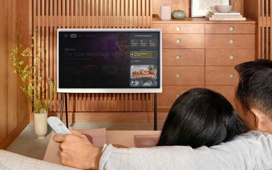 Koppel kijkt televisie met Google TV afstandsbediening in de hand.