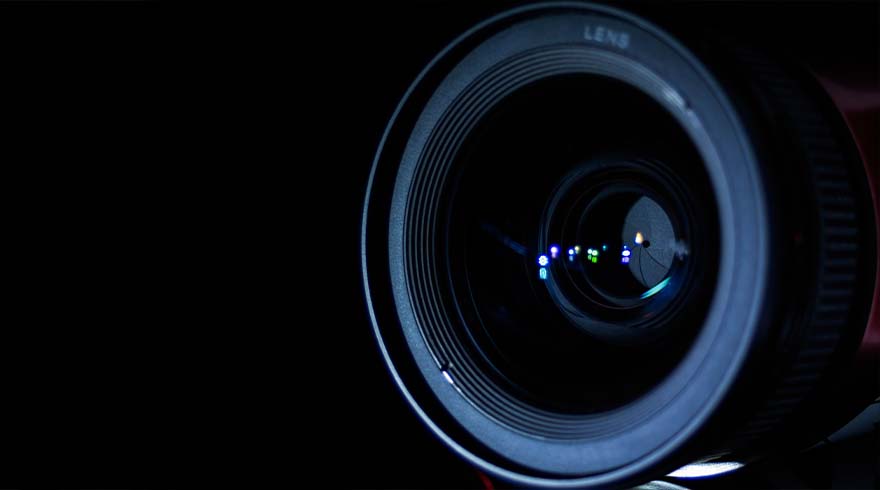 Een close-up van een cameralens tegen een zwarte achtergrond, met reflecties zichtbaar in het glas.