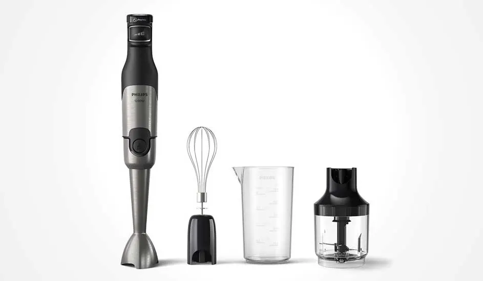 Donkergrijze Philips staafmixer met metalen voet, met ernaast een garde-opzetstuk, maatbeker en kleine hakmolen op witte achtergrond.
