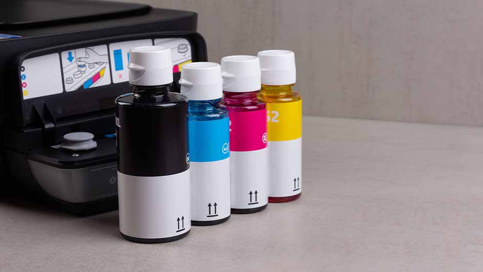 Een printer staat naast vier inktflessen in de kleuren zwart, blauw, roze en geel, met witte doppen en witte labels.