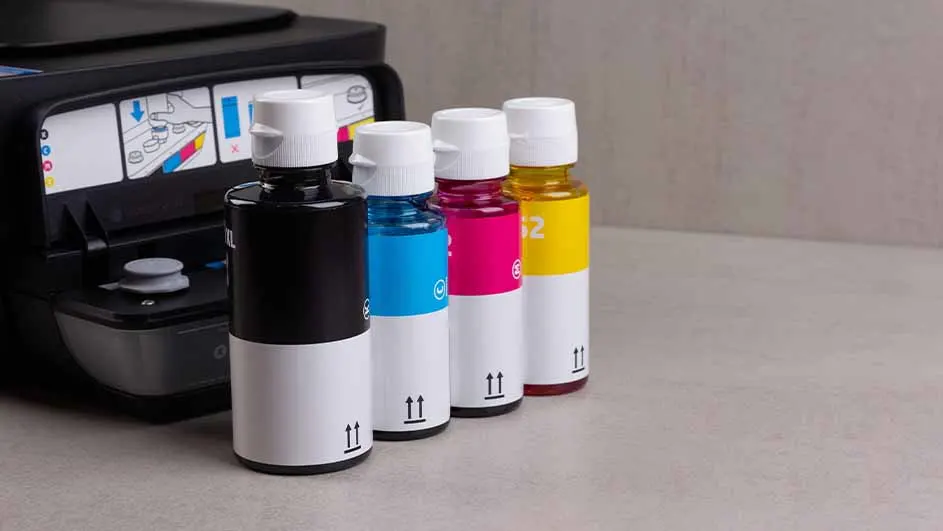 Een printer staat naast vier inktflessen in de kleuren zwart, blauw, roze en geel, met witte doppen en witte labels.