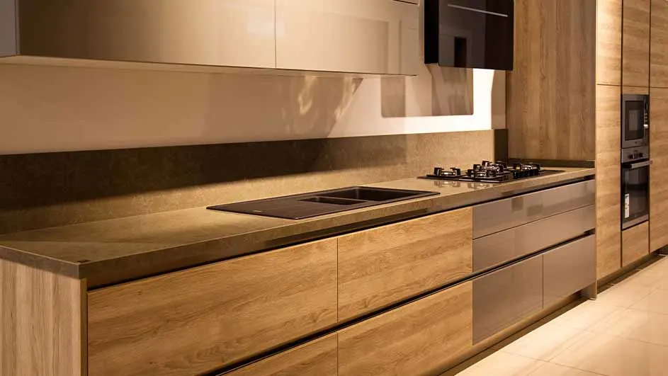 Houten keukenkasten met een aanrechtblad, een spoelbak, een kookplaat en een oven in de achtergrond.